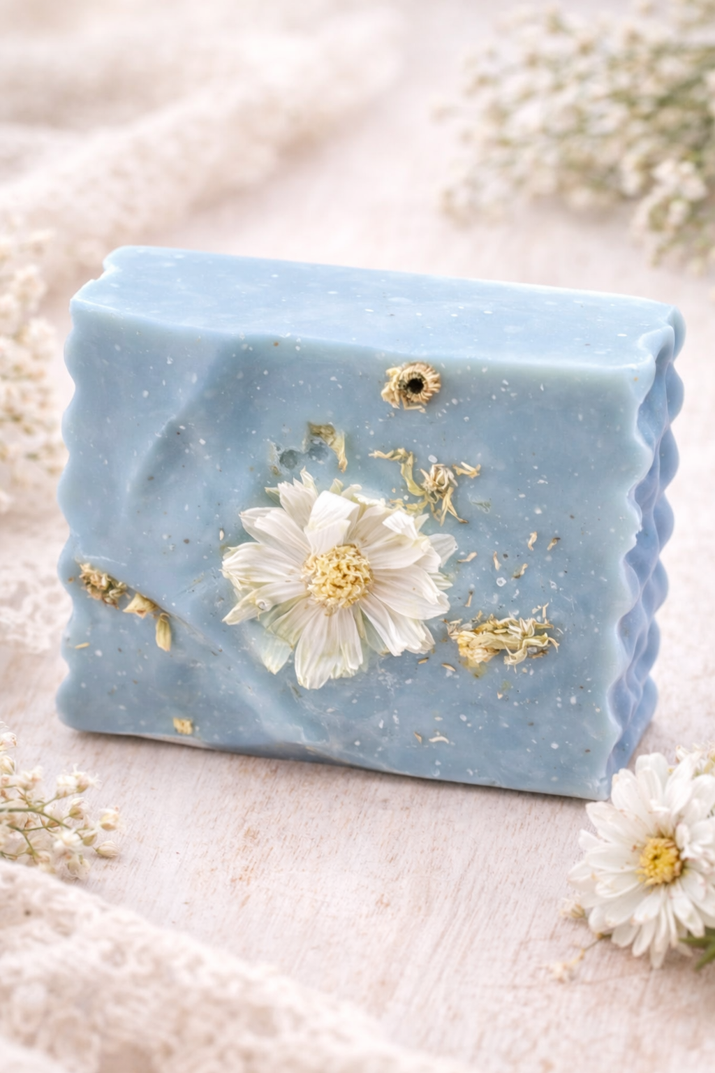 blue soap with floral daisy background on a beige linen cloth with flowers in the background. 