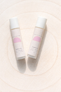 Two lip balm tubes with a pink label on a light beige background