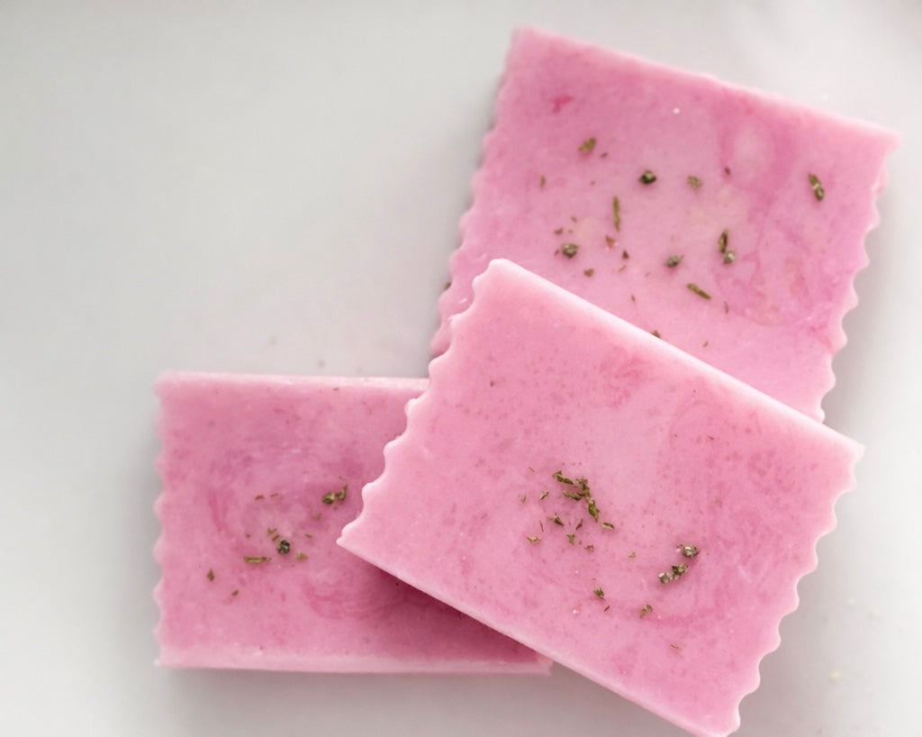 Three pink soap bars with  lilac heather flowers on a white background