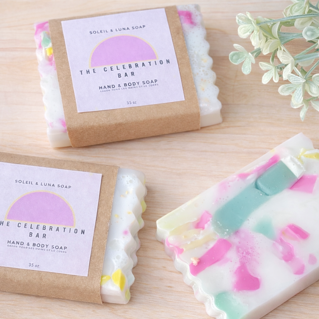Handmade soap bars with colorful design and 'The Celebration Bar' packaging on a wooden surface.